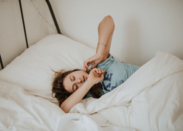 chica durmida en la cama tocando las mandibulas