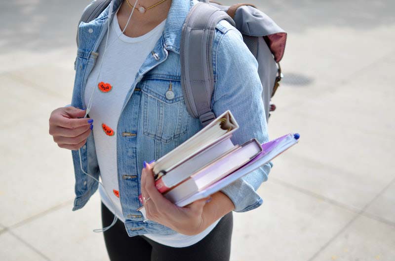 chica estudiante de fitoterapia en la calle sujeta libros