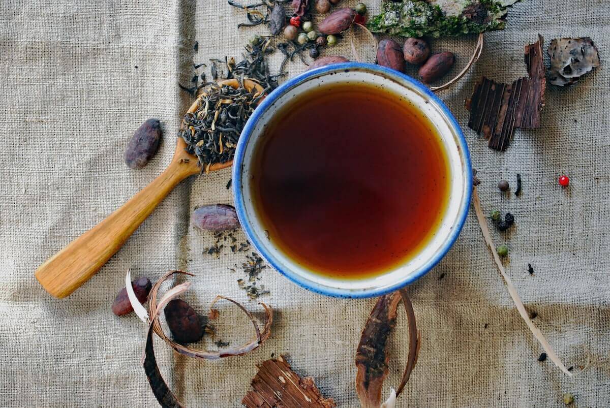 taza de infusión y hierbas a granel en una mesa