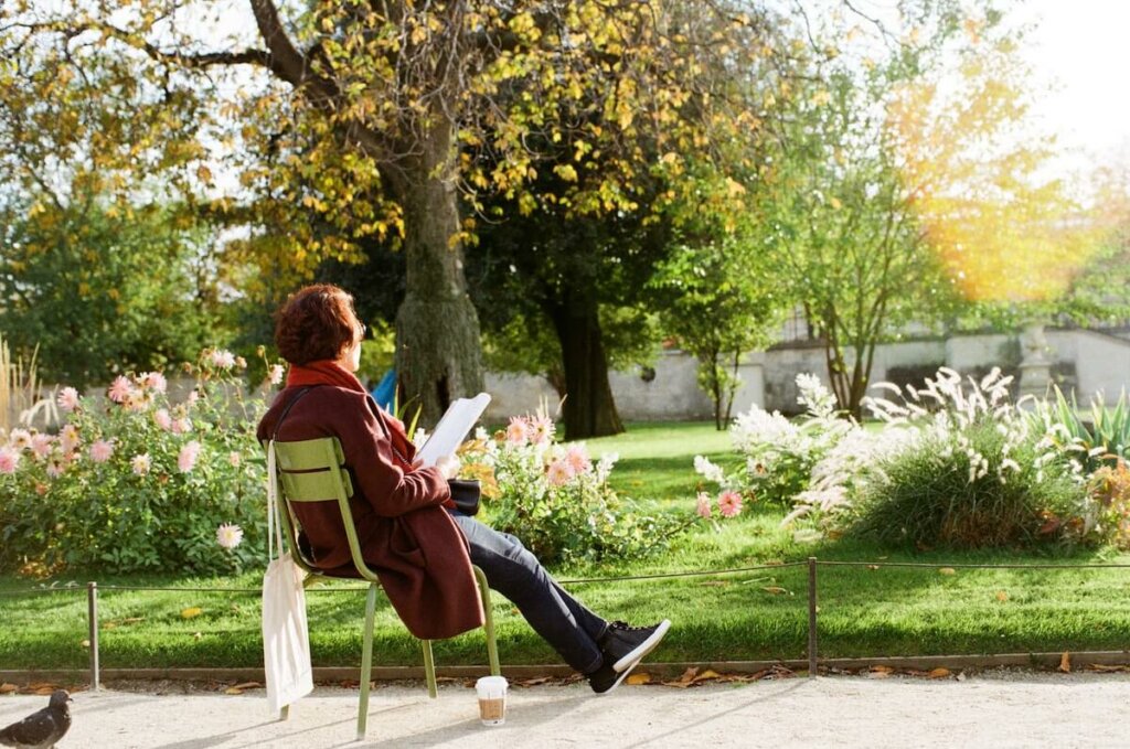 una mujer amante de la naturaleza lee sentada en un parque entre flores