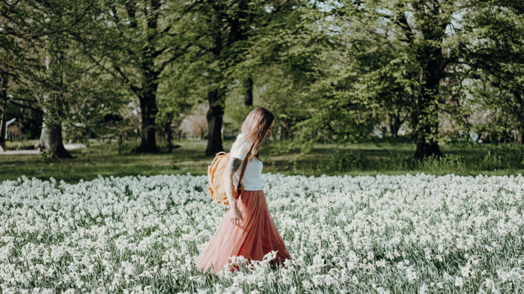 mujer pasea por el campo entre flores